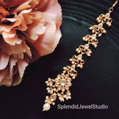 a close up of a necklace on a black plate with flowers in the back ground