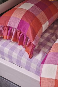 a pink and orange checkered comforter on top of a bed with two pillows