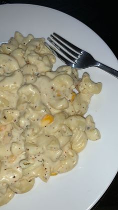 a white plate topped with macaroni and cheese covered in sauce next to a fork