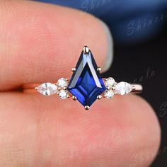 a woman's hand holding an engagement ring with blue and white stones on it