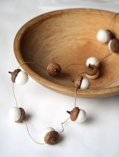 some white and brown balls are in a wooden bowl on a white tablecloth with string