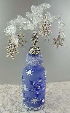 a blue glass vase with snowflakes and stars on the top is sitting on a lace tablecloth