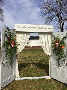 an open door with flowers and greenery on it