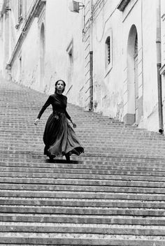 a woman in a long dress is walking up some stairs