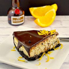 a piece of cheesecake on a white plate with chocolate icing and orange slices