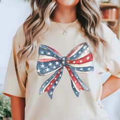 Custest little miss America patriotic oversized bow tee! Comfort Colors introduces the "Comfort Colors 1717" garment-dyed t-shirt; a fully customizable tee made 100% with ring-spun cotton. The soft-washed, garment-dyed fabric brings extra coziness to your wardrobe while the relaxed fit makes it an excellent daily choice. The double-needle stitching throughout the tee makes it highly durable while the lack of side-seams helps the shirt retain its tubular shape. Discover all 58 colors in our Comfort Colors 1717 color charts below. .: The Comfort Colors 1717 tee is made with medium fabric (6.1 oz/yd² (206.8 g/m consisting of high quality, 100% ring-spun US cotton for long-lasting comfort. .: The relaxed fit keeps the wearer comfy in both casual and semi-formal settings while the crew neckline Cute American Flag Print Short Sleeve T-shirt, America Outfit, Patriotic Bows, Bow Shirt, Bow Shirts, Miss America, Dyed Fabric, Little Miss, Dye T Shirt