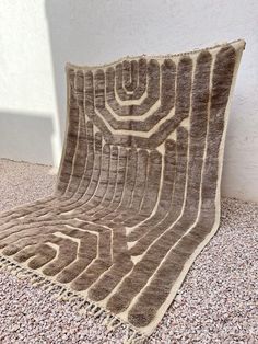 a brown and white rug sitting on top of a stone floor next to a wall