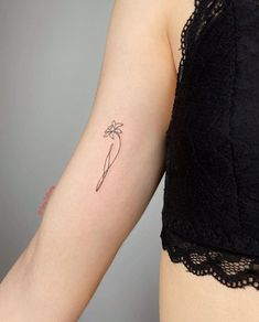 a woman's arm with a small flower tattoo on the left side of her arm