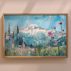 a painting hanging on the wall with flowers in front of it and a mountain behind it