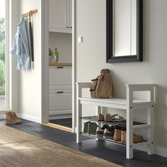 a white bench sitting under a mirror next to a coat rack with shoes on it