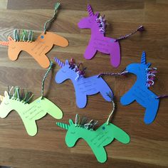 colorful unicorns are hanging from string on a wooden table with note attached to them