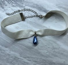 Soft white and sparkle ribbon ending with a lobster claw necklace closure, featuring a beautiful blue drop pendant in the center. Blue Jewelry Aesthetic, White Necklaces, Fantasy Crown, Necklace Closure, Claw Necklace, Ribbon Ends, Blue Jewelry, Historical Dresses, Choker Necklaces