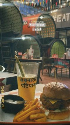 a burger and fries are sitting on a table in front of a glass with a beverage