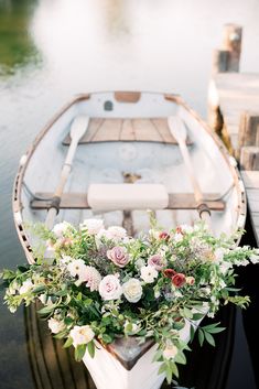 a boat with flowers on the front is tied to a dock and docked at the water's edge