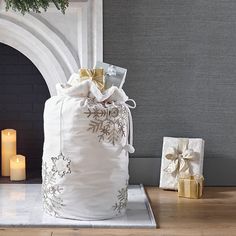 a white bag sitting on top of a wooden floor next to two candles and presents