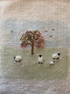 there are sheep and a tree in the middle of a field with pink flowers on it