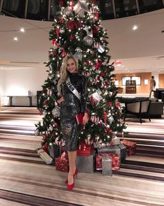 a woman standing in front of a christmas tree