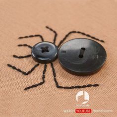 a black spider button sitting on top of a piece of cloth next to a hole in the fabric