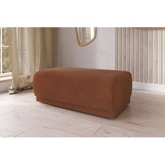 a large brown couch sitting on top of a hard wood floor next to a window