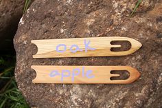 two wooden utensils with the words oak and apple written on them sitting on top of a rock