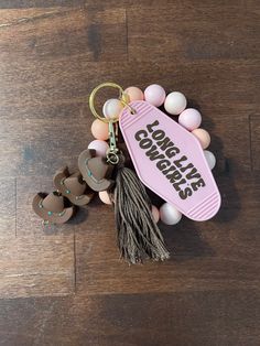 a pink keychain with some tassels attached to it on a wooden floor