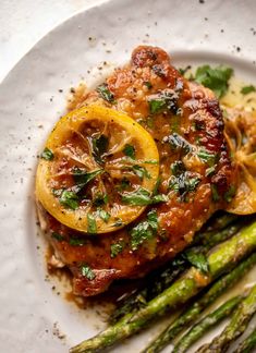 a white plate topped with meat and asparagus