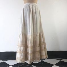 Antique Victorian cotton maxi skirt has horizontal pleats, and lace ribbon insets at the hem. The skirt has clasp closures, and an underskirt at the hem portion of the skirt. ConditionStructurally good, with issues. Has overall yellowing, with darker areas, and stains throughout but most prominently in the hem area. There are tiny dot stains on the upper skirt portion. There’s two area of holes in the lace at the hem.  The underskirt has staining throughout. We have not attempted to clean this i Beige Long Skirt With Lace Trim, Daywear Tiered Gathered Petticoat, Beige Cotton Skirt With Lace Trim, Elegant Cotton Maxi Skirt For Daywear, Fitted Beige Maxi Skirt For Daywear, Elegant Ruffled Maxi Skirt For Daywear, Long Cotton Skirt With Lace Trim, Cotton Skirt With Lace Trim For Daywear, Cotton Long Skirt With Lace Trim