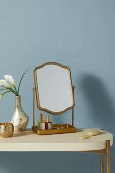 a table with a mirror, vase and other items on it