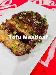 meatloaf with sauce and green onions on a white plate next to a red tablecloth