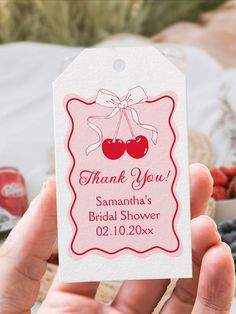 a person holding up a thank you tag with cherries on it and berries in the background