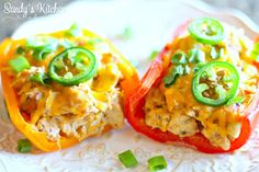 two stuffed peppers on a white plate with green onions