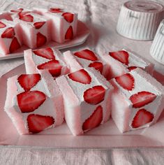 strawberry shortbreads with white frosting and sliced strawberries on the top, sitting on a pink plate