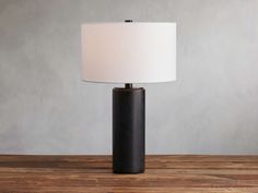 a black table lamp sitting on top of a wooden table next to a white lampshade