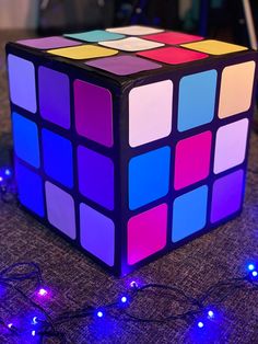 a rubik cube sitting on top of a table covered in blue and pink lights