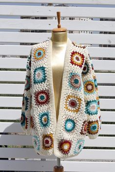 a white crocheted sweater with multicolored circles on it sitting on a mannequin