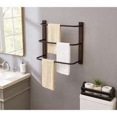 a towel rack with three towels hanging from it's sides in a bathroom next to a sink