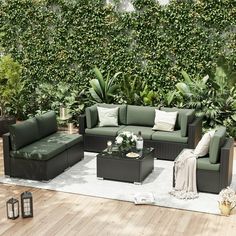 an outdoor living room with lots of furniture and greenery on the wall behind it