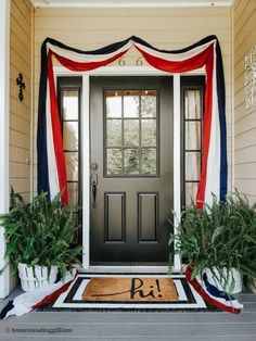 the front door is decorated with red, white and blue ribbon as well as potted plants