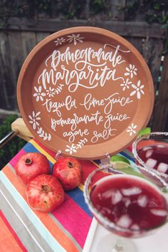 two glasses of juice and some apples on a table with a sign that says homemade margarita