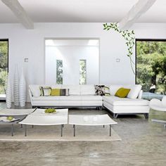 a modern living room with white furniture and large windows