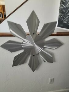 a metal flower on the wall next to a stair case in a room with white walls