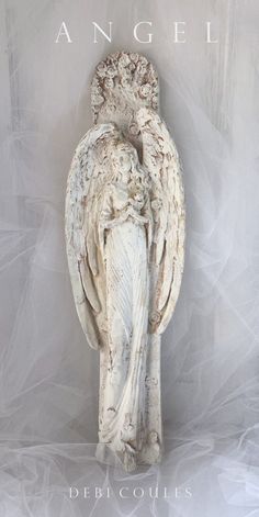 an angel statue sitting on top of a white sheet covered ground with the words angel above it