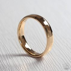 a gold wedding ring sitting on top of a white table