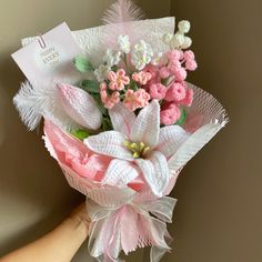 a hand holding a pink and white bouquet with flowers in it's centerpiece