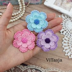 three crocheted flowers are shown in the palm of a person's hand