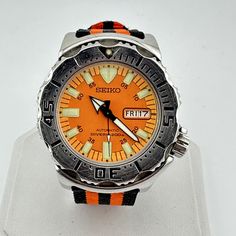 Seiko 1st Generation Orange Monster SKX781 43mm Automatic Dive Watch 7S26-0350 Equipped with an awesome orange and black striped nylon NATO style strap. This is an awesome, eye-catching watch!   The lume on the hands and indices is brighter than anything else I've ever seen, and glows through the night. The 7s26a 21 Jewel automatic movement is working great, keeps good time and has more than enough reserve power to make it through the night and then some. The unidirectional bezel is in decent sh Orange Analog Watch With Round Dial, Orange Monster, Shinola Watch, Divers Watch, Nato Strap, Dive Watches, Make It Through, Black Nylon, Vintage Fabrics