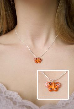 a woman wearing a necklace with an orange butterfly on it's back and the bottom part of her chest