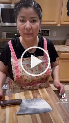 a woman in an apron preparing food on a cutting board with a knife and spatula