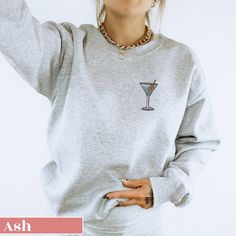 Elevate your casual wardrobe with our Embroidered Dirty Martini Sweatshirt! This cozy and stylish sweatshirt features a beautifully detailed martini glass with olive embroidery. Perfect for those who appreciate a touch of sophistication in their everyday wear, this sweatshirt combines comfort with a chic design. Made from high-quality fabric, it provides warmth and durability, making it an ideal addition to your closet. Whether you're lounging at home or stepping out for a casual outing, this em Casual Crew Neck Sweater For Party, Trendy Party Sweater With Crew Neck, Trendy Crew Neck Sweater For Party, Casual Party Sweatshirt, Casual Long Sleeve Party Sweatshirt, Casual Winter Party Sweatshirt, Winter Party Sweatshirt With Crew Neck, Winter Party Crew Neck Sweatshirt, Olive Embroidery