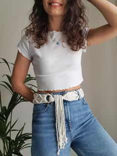 a woman in white shirt and jeans posing with her hands on her head while wearing a belt